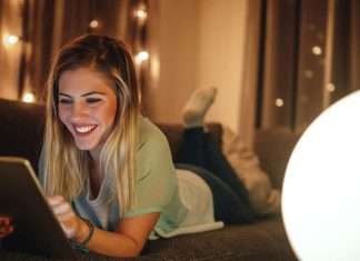 De 10 bedste websteder til download af gratis e-bøger En ung kvinde ligger på en sofa og bruger en tablet. Baggrunden er oplyst med små lys, hvilket skaber en hyggelig atmosfære.