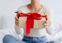 En pige med en gave i hænderne sidder på sengen.