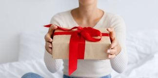 En pige med en gave i hænderne sidder på sengen.