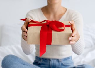 En pige med en gave i hænderne sidder på sengen.