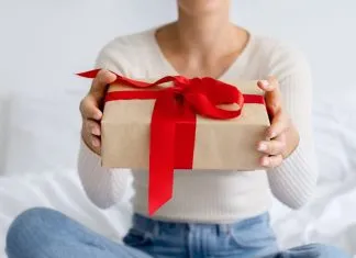 Derfor skal du ikke stole på giveaway-konkurrencer på sociale medier En pige med en gave i hænderne sidder på sengen.