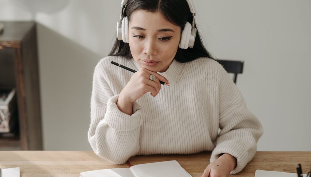 En pige med høretelefoner, der studerer ved sit skrivebord.