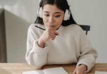 En pige med høretelefoner, der studerer ved sit skrivebord.