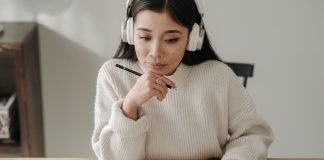 En pige med høretelefoner, der studerer ved sit skrivebord.