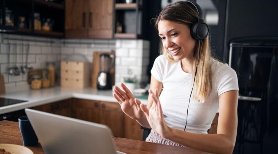 En pige sidder med høretelefoner på foran en bærbar computer.