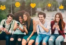 Fem unge mennesker sidder på en bænk med smartphones