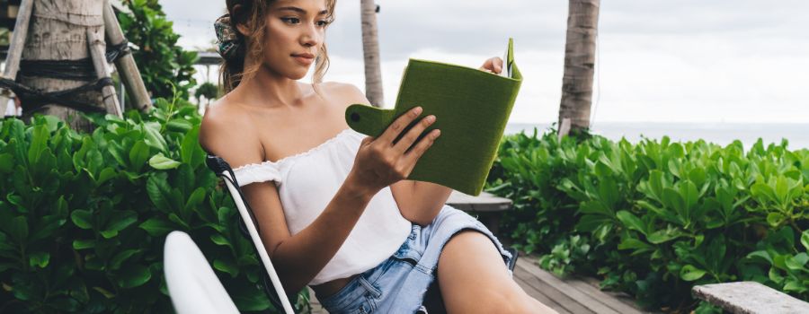 En pige sidder på en bænk med en e-bog i hænderne
