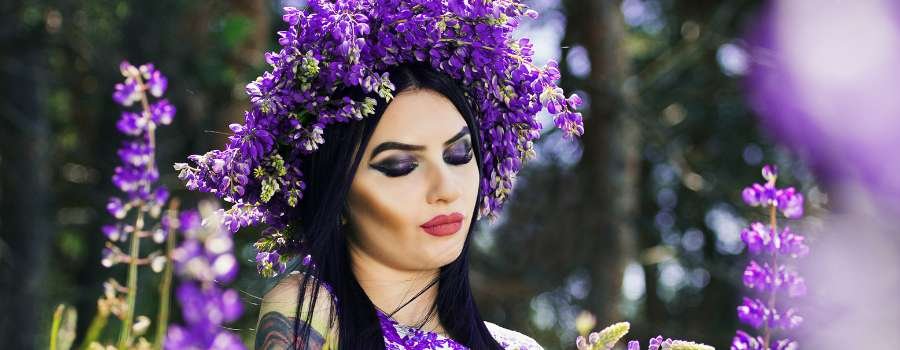 Pigemodel i skov med buket af lilla blomster og krans på hovedet lavet af lilla blomster