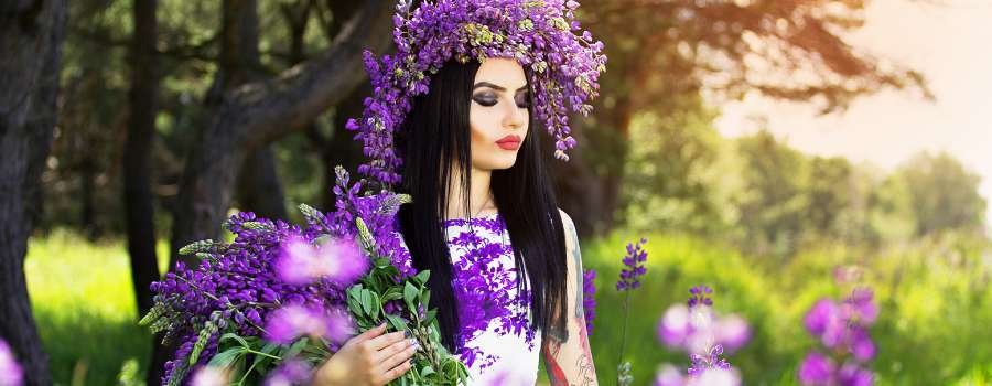 Pigemodel i skov med buket af lilla blomster og krans på hovedet lavet af lilla blomster