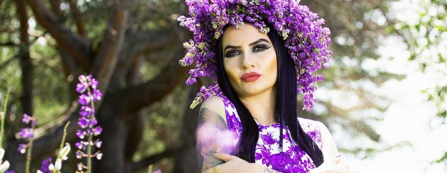 Pigemodel i skov med buket af lilla blomster og krans på hovedet lavet af lilla blomster