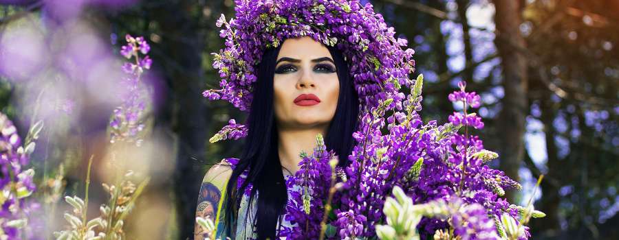 Pigemodel i skov med buket af lilla blomster og krans på hovedet lavet af lilla blomster