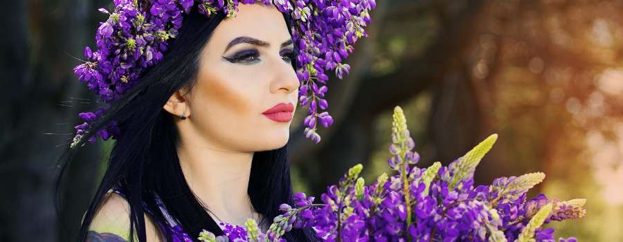 Pigemodel i skov med buket af lilla blomster og krans på hovedet lavet af lilla blomster