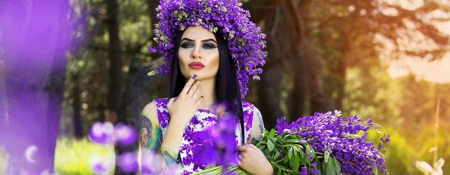 Pigemodel i skov med buket af lilla blomster og krans på hovedet lavet af lilla blomster