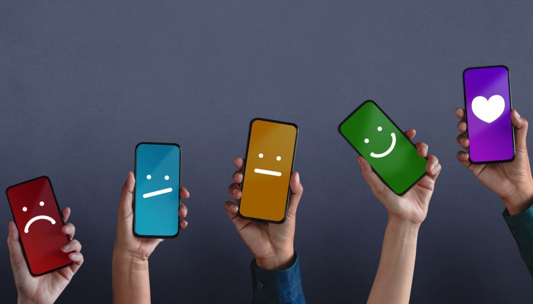 smartphones Fem hænder rakte op med smartphones, hvis skærme viser forskellige smileys på forskellige farvede baggrunde