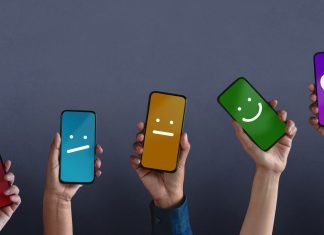 Fem hænder rakte op med smartphones, hvis skærme viser forskellige smileys på forskellige farvede baggrunde