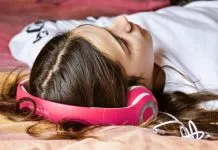 Top 6 hjemmesider til download af royaltyfri musik til dit næste projekt En pige med høretelefoner ligger på gulvet.