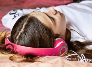 Top 6 hjemmesider til download af royaltyfri musik til dit næste projekt En pige med høretelefoner ligger på gulvet.