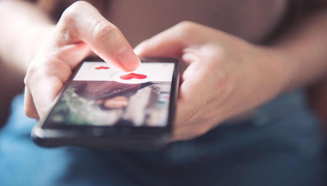 En pige holder en smartphone med en dating-app åben.