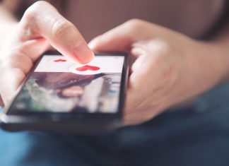 En pige holder en smartphone med en dating-app åben.