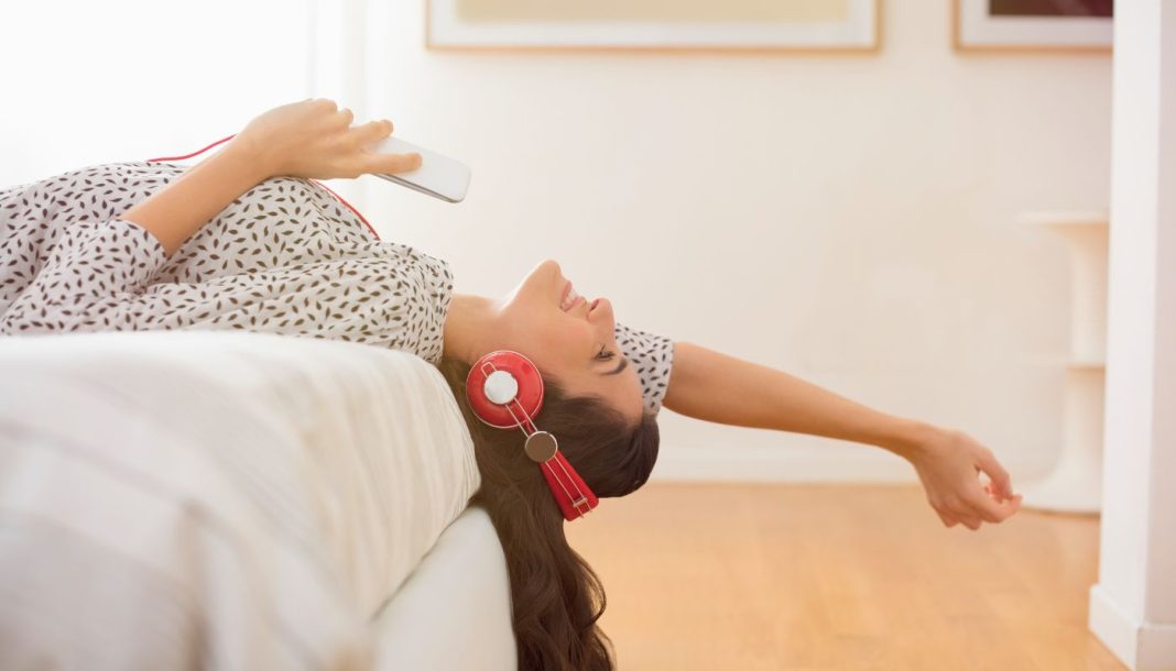 En pige med høretelefoner ligger på sengen.