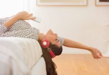 Betaler du for at streame musik? 6 gratis alternativer, der er værd at tjekke ud En pige med høretelefoner ligger på sengen.