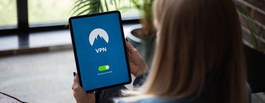 Gratis vs. betalte VPN'er: Hvilken skal du vælge? 1 En pige med en tablet i hænderne, hvor vpn er aktiveret på tablettens skærm.