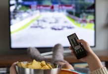 De bedste streamingtjenester til 4K-indhold En pige med en skål popcorn og en fjernbetjening i hånden sidder foran fjernsynet