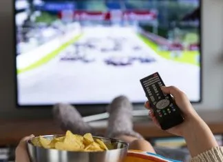 De bedste streamingtjenester til 4K-indhold En pige med en skål popcorn og en fjernbetjening i hånden sidder foran fjernsynet