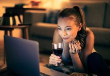 Sådan tjekker du, hvilke film der er tilgængelige for streaming En pige med et glas vin sidder i en sofa foran en bærbar computer