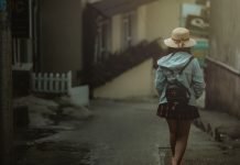 En pige med en sort rygsæk bag sig går ned ad en gade i byen.