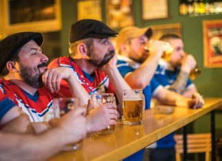 Koncentrerede mænd ser live sportskamp i baren