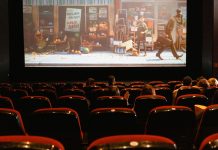 Usikker på, hvad du skal se på dine streamingtjenester? Tryk på denne knap Biografsal med mennesker, der ser en animationsfilm på en stor skærm, med delvist fyldte røde sæder.