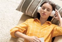 De 5 bedste apps til at downloade musik gratis på Android Pige med hovedtelefoner ligger på en sofa og lytter til musik med lukkede øjne.