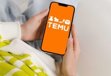 En persons hænder, der holder en smartphone med TEMU-logoet på en orange baggrund.