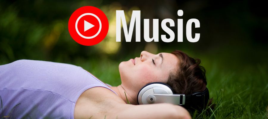 En pige ligger på græsset med høretelefoner, YouTube Music-logoet er placeret øverst i midten.