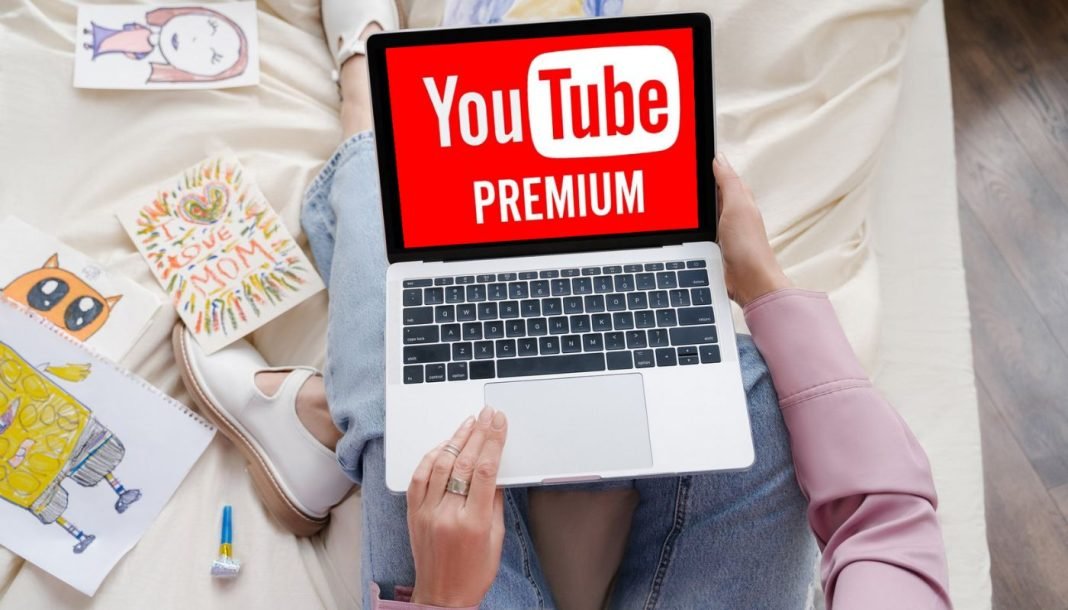 Kvinde med en bærbar computer på skødet, hvor YouTube Premium-logoet vises på skærmen.