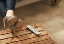 6 niche-streamingtjenester, der tilbyder mere fokuseret indhold end Netflix Kvinde ben i højhælede sko, afslappet hvilende på et træbord ved siden af en fjernbetjening.