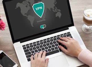 Her er, hvad en VPN faktisk skjuler, og hvordan den beskytter dine data En person bruger en bærbar computer, hvor skærmen viser, at en VPN-forbindelse er ved at blive oprettet. På bordet ved siden af computeren er der en smartphone, en kop kaffe og en vase med lyserøde roser