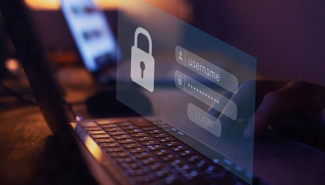 En nærbillede af en persons hænder, der taster et brugernavn og en adgangskode ind på en bærbar computer. Skærmen viser et login-vindue med et ikon af en lås.