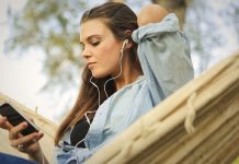 En pige sidder i en hængekøje og lytter til musik med øretelefoner.