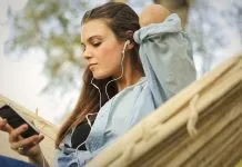 En pige sidder i en hængekøje og lytter til musik med øretelefoner.