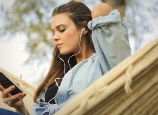 En pige sidder i en hængekøje og lytter til musik med øretelefoner.