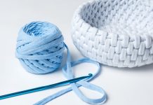 En hæklenål, et nøgle lyseblåt garn og en hæklet hvid kurv.