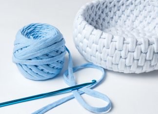 En hæklenål, et nøgle lyseblåt garn og en hæklet hvid kurv.