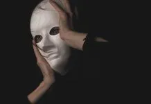 13 bedste deepfake apps: Lav realistiske og imponerende AI-videoer selv En person holder en hvid maske foran ansigtet i en mørk og mystisk atmosfære.