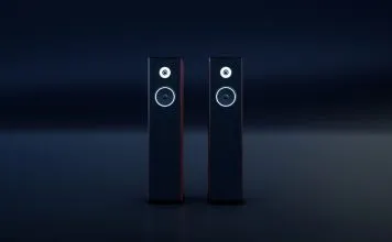 To sorte, slanke hi-fi-højttalere med hvide ringe omkring enhederne står side om side i et mørkt rum.